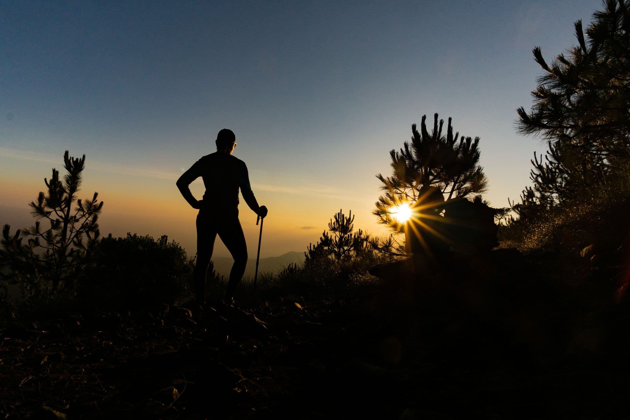 Silhouette of a hiker on a hilltop at sunset