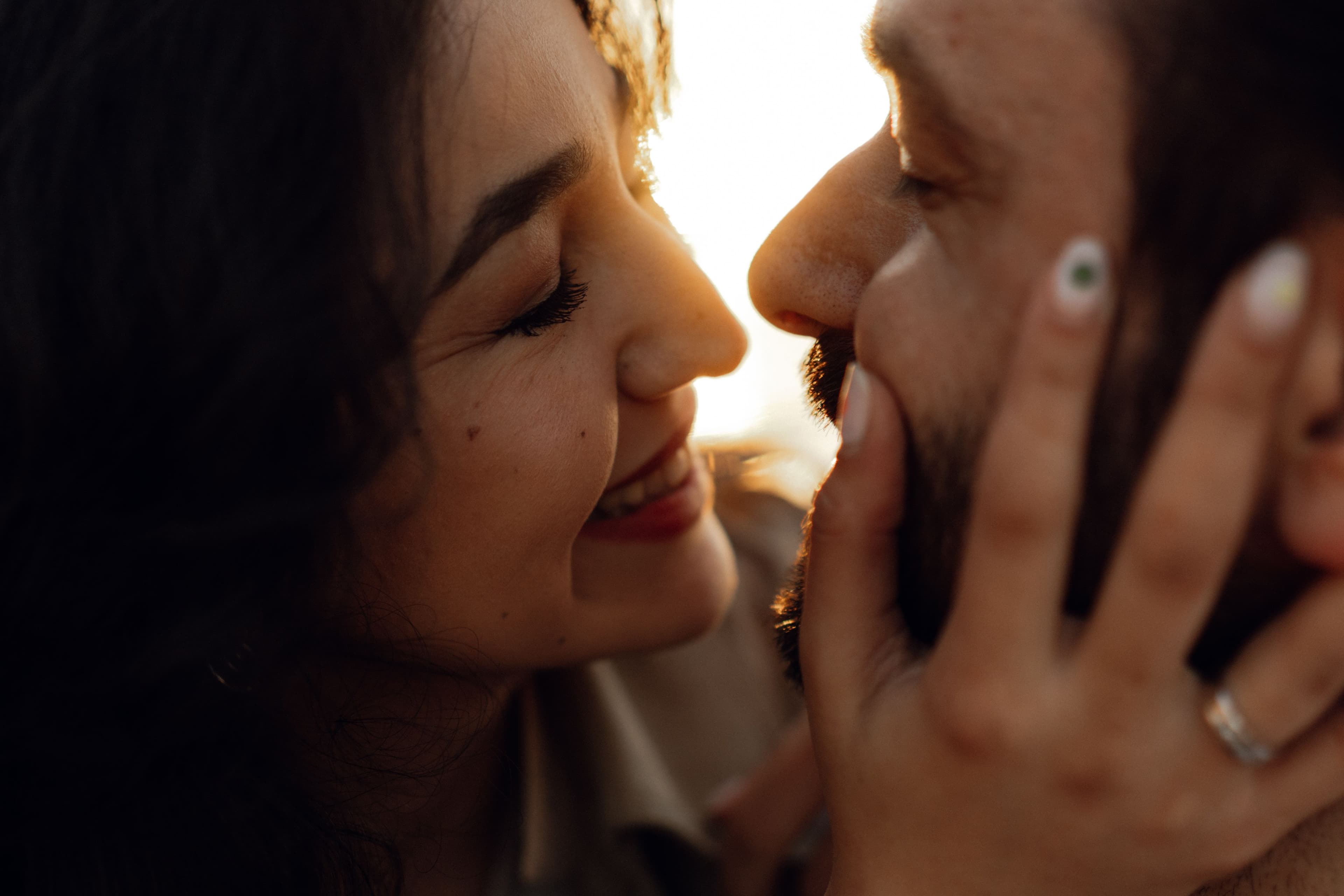 Close-up of a smiling couple embracing, her hand on his cheek