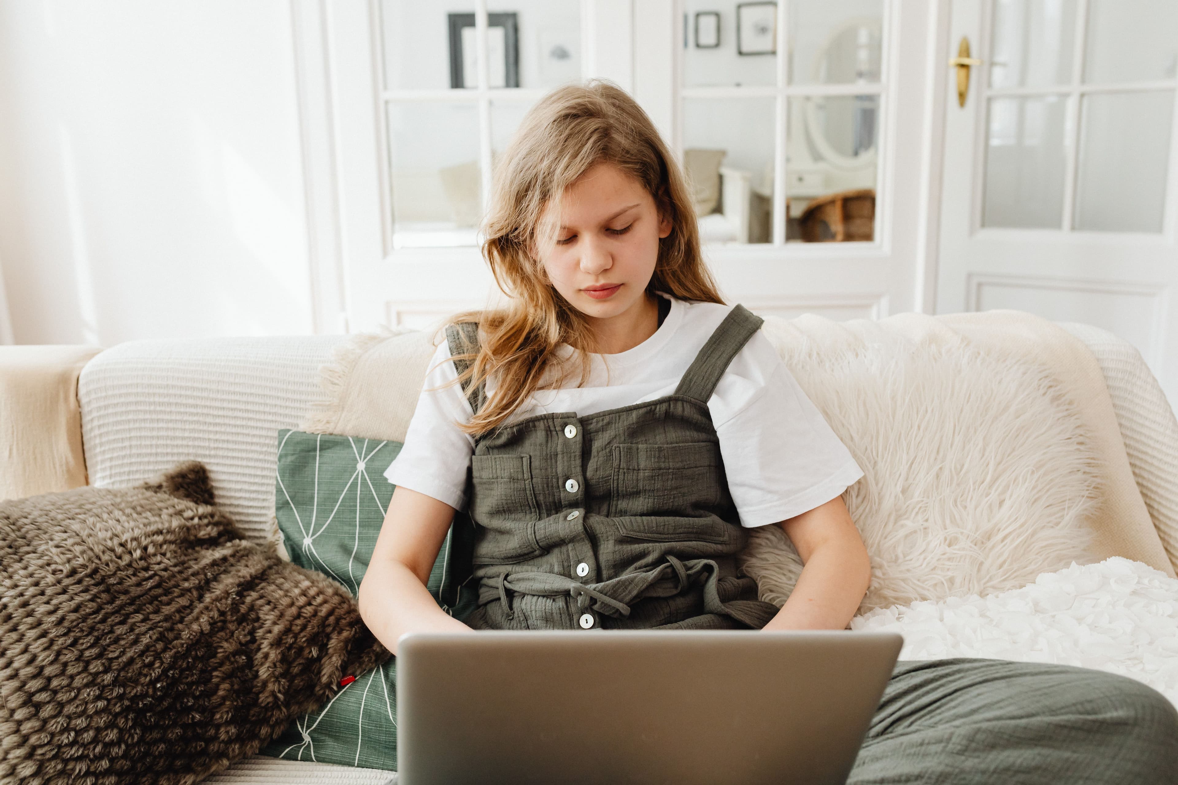 Teenage girl using a laptop on a sofa at home