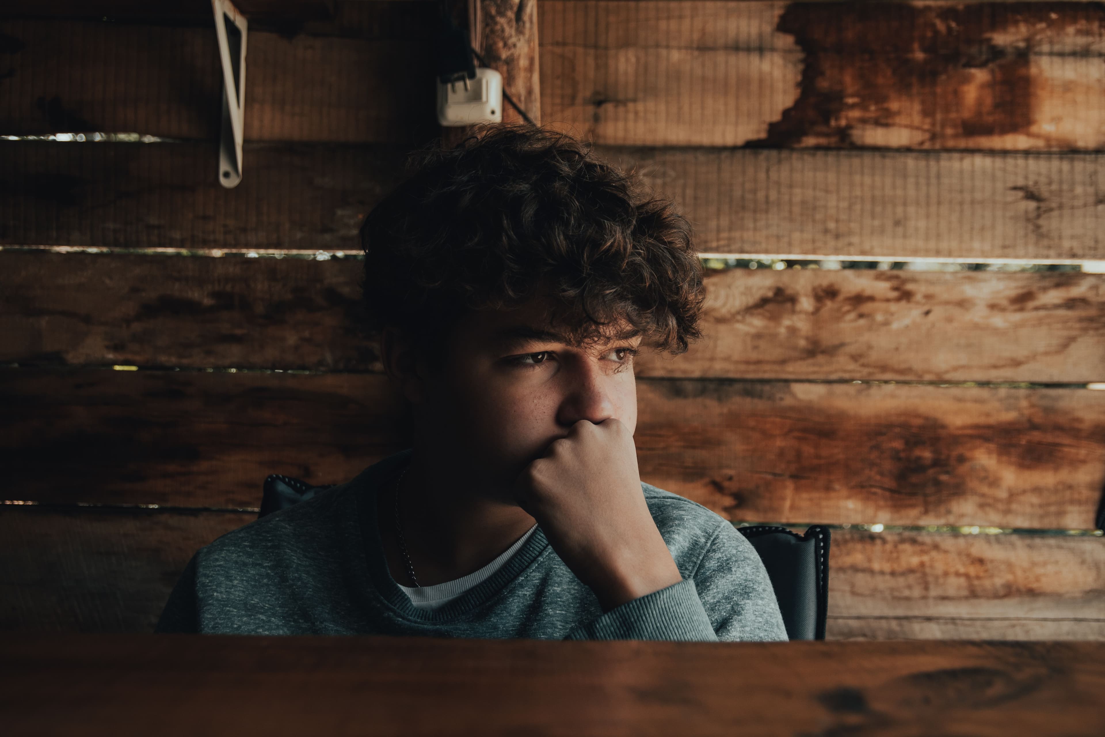 Thoughtful teenage boy resting his chin on his hand