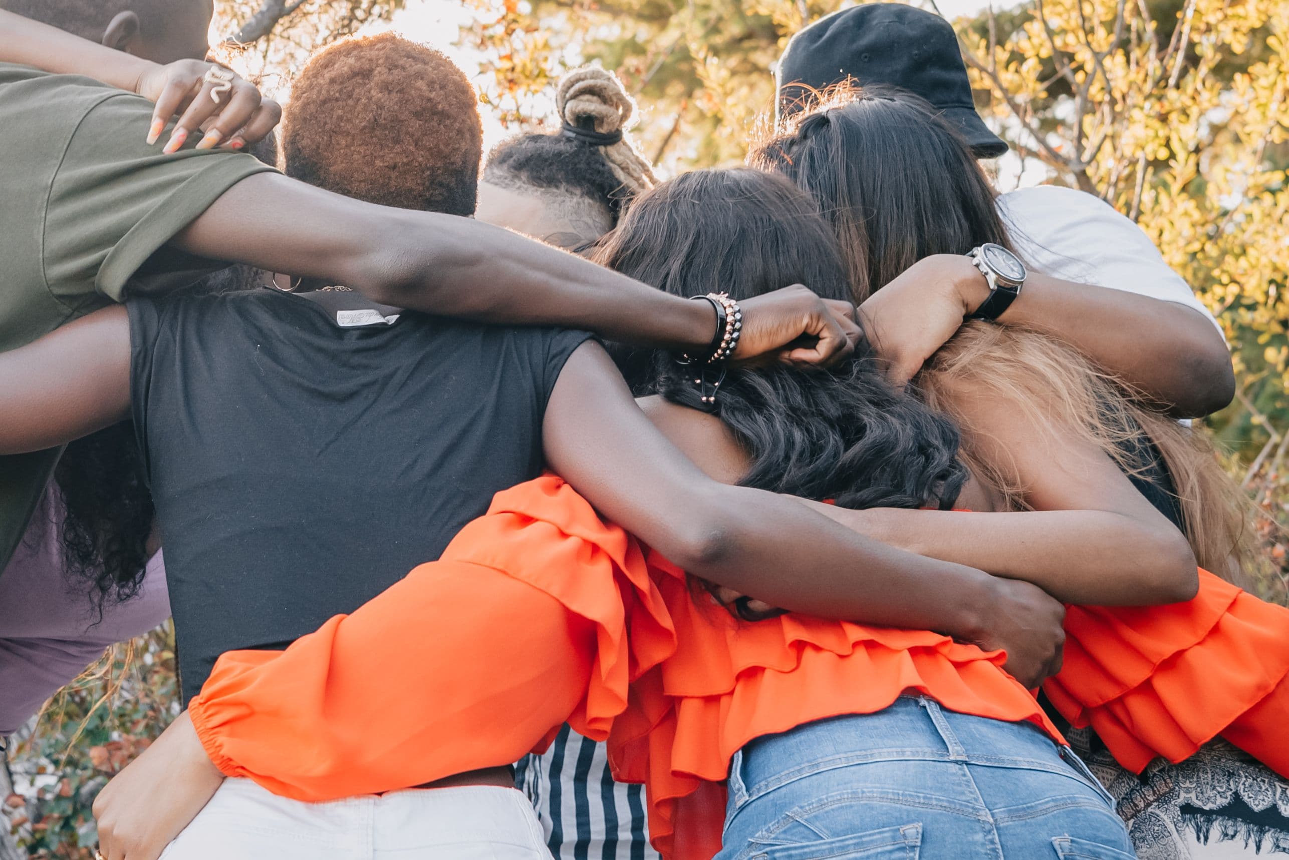 Group of friends with their arms around each other, seen from behind
