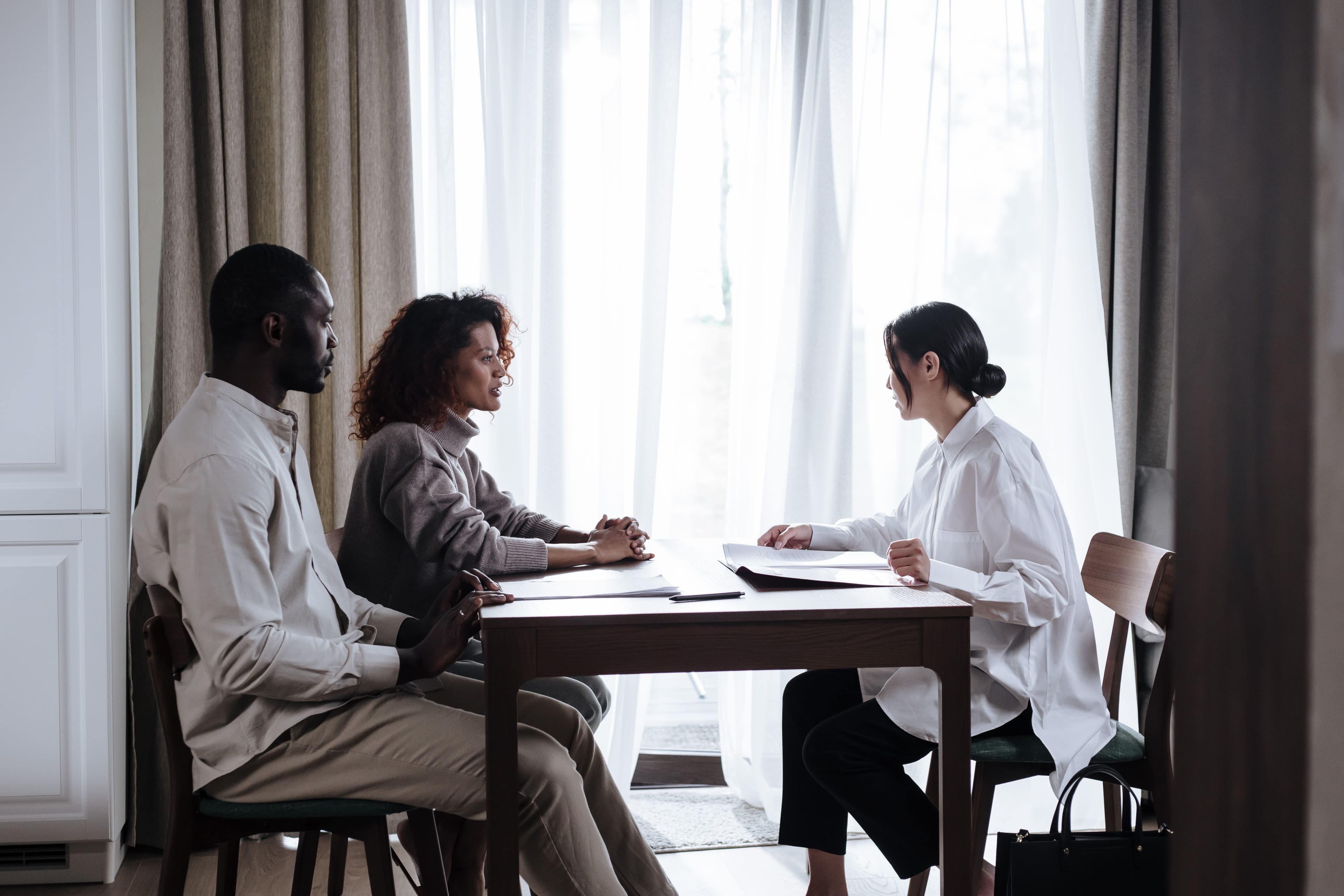 Three professionals meeting at a table by a bright window